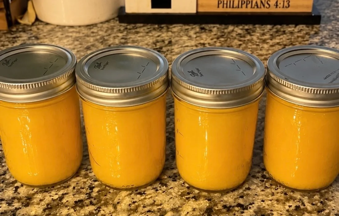 Four sealed 16oz mason jars of fresh orange juice lined up on a granite kitchen counter